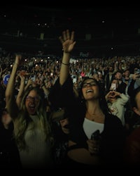 a group of people at a concert with their hands up